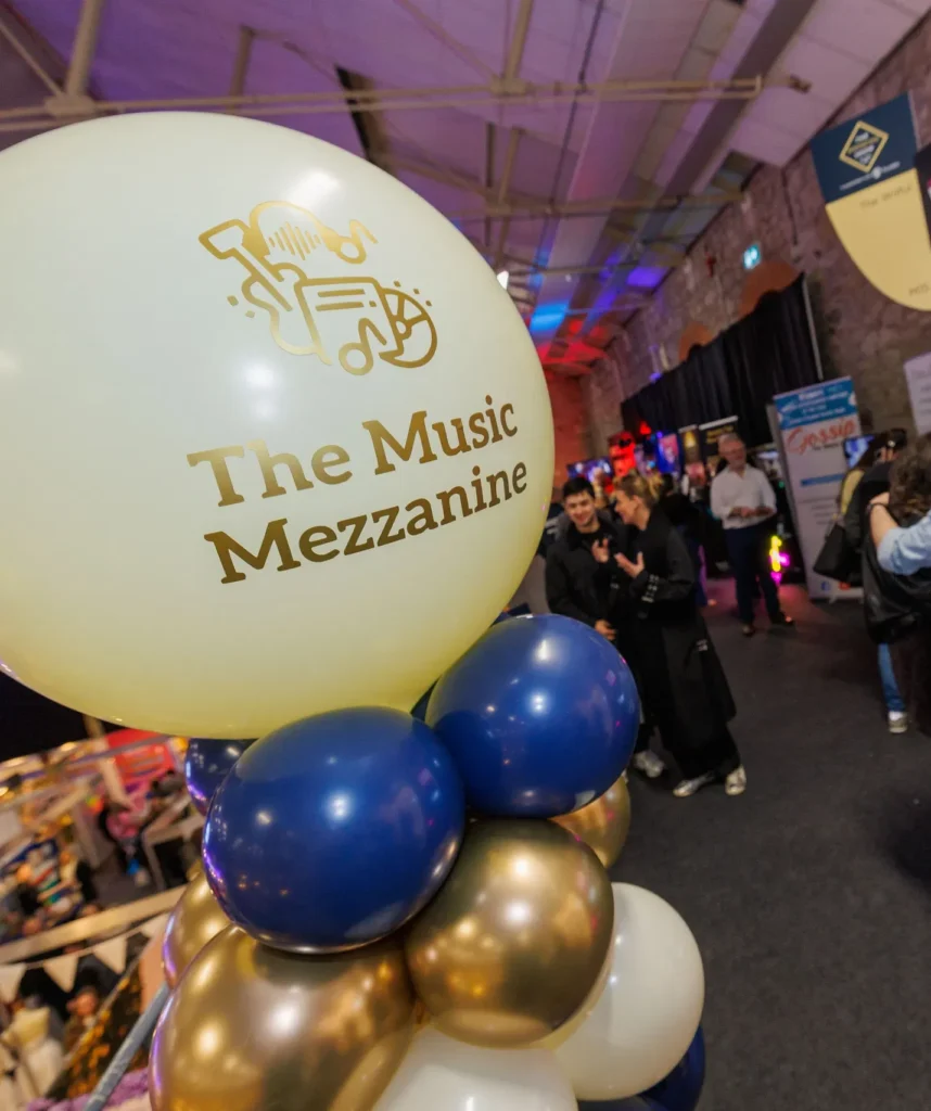 Balloon display at The Music Mezzanine event with people mingling in the background.