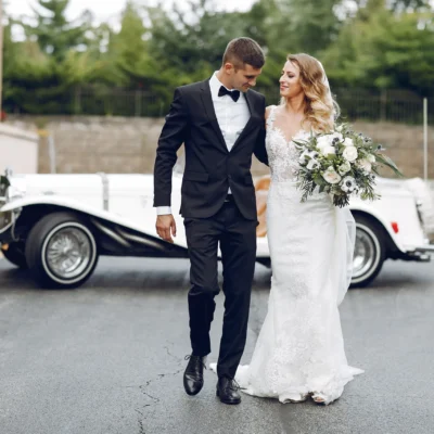 Man and woman in wedding with a wedding car behind