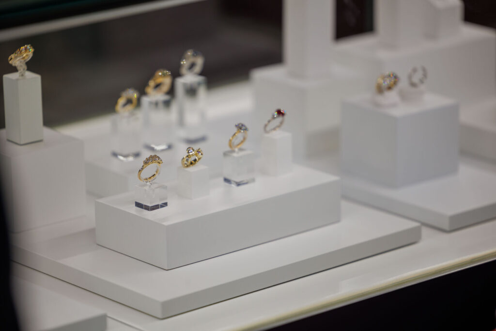 Luxury gold rings elegantly displayed on white stands in a jewelry store.