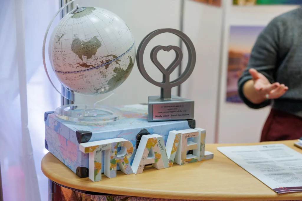 Globe and travel award displayed on desk at travel event, with a person's hand gesturing nearby.